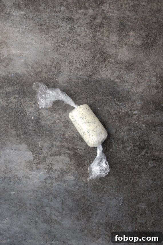 Garlic compound butter shaped into a log and sealed inside plastic wrap.