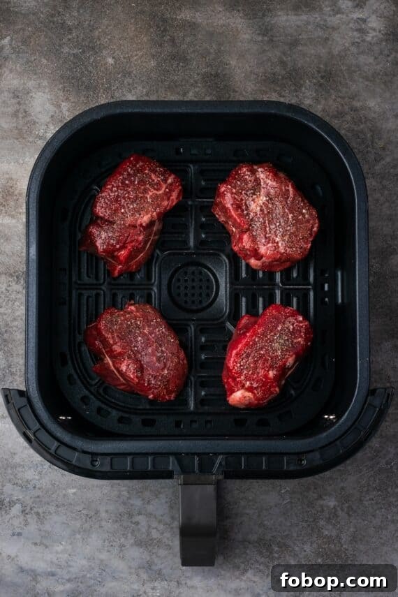 Four seasoned filet mignon steaks inside the air fryer.