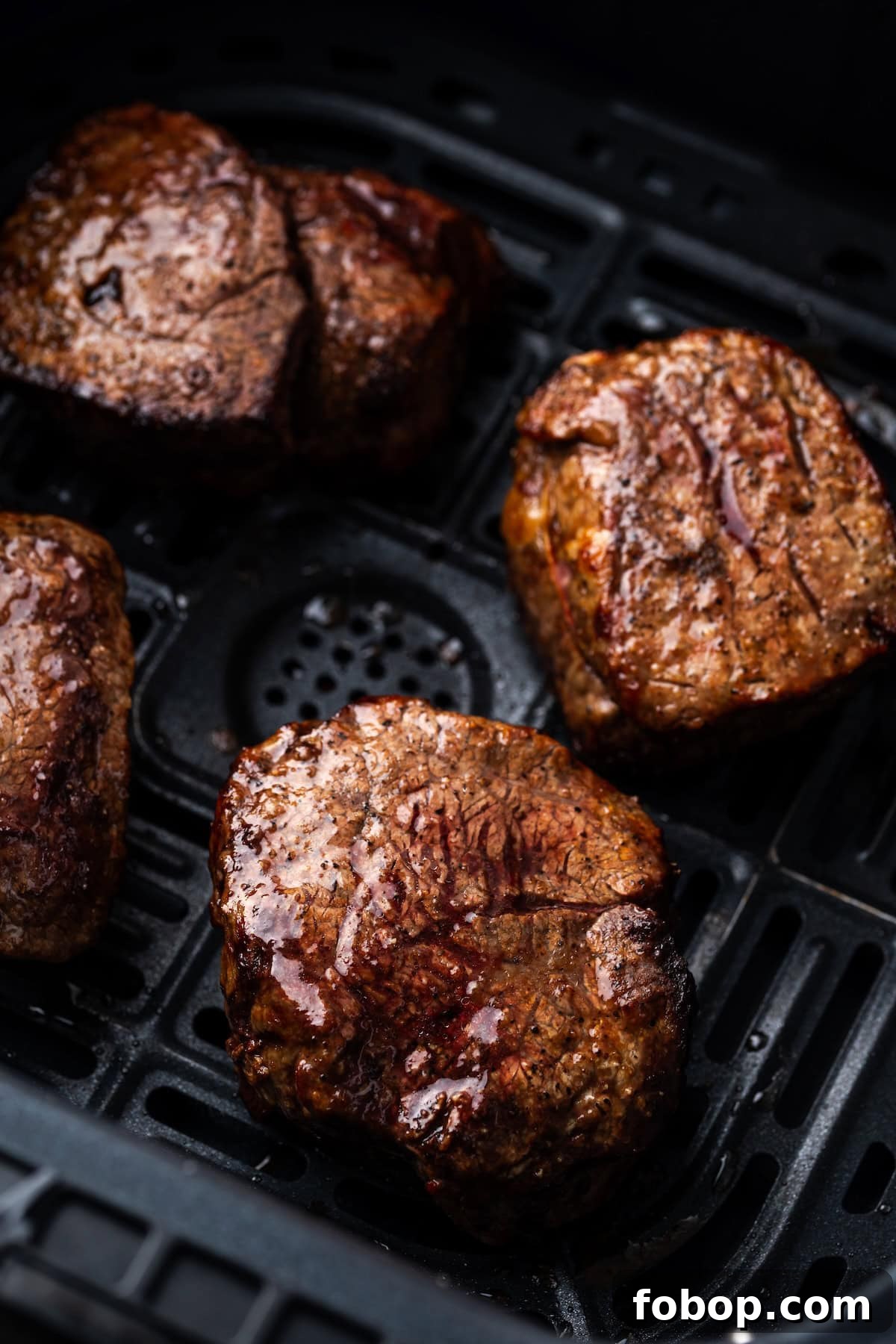 Close up of cooked filet mignon steaks inside the air fryer basket.