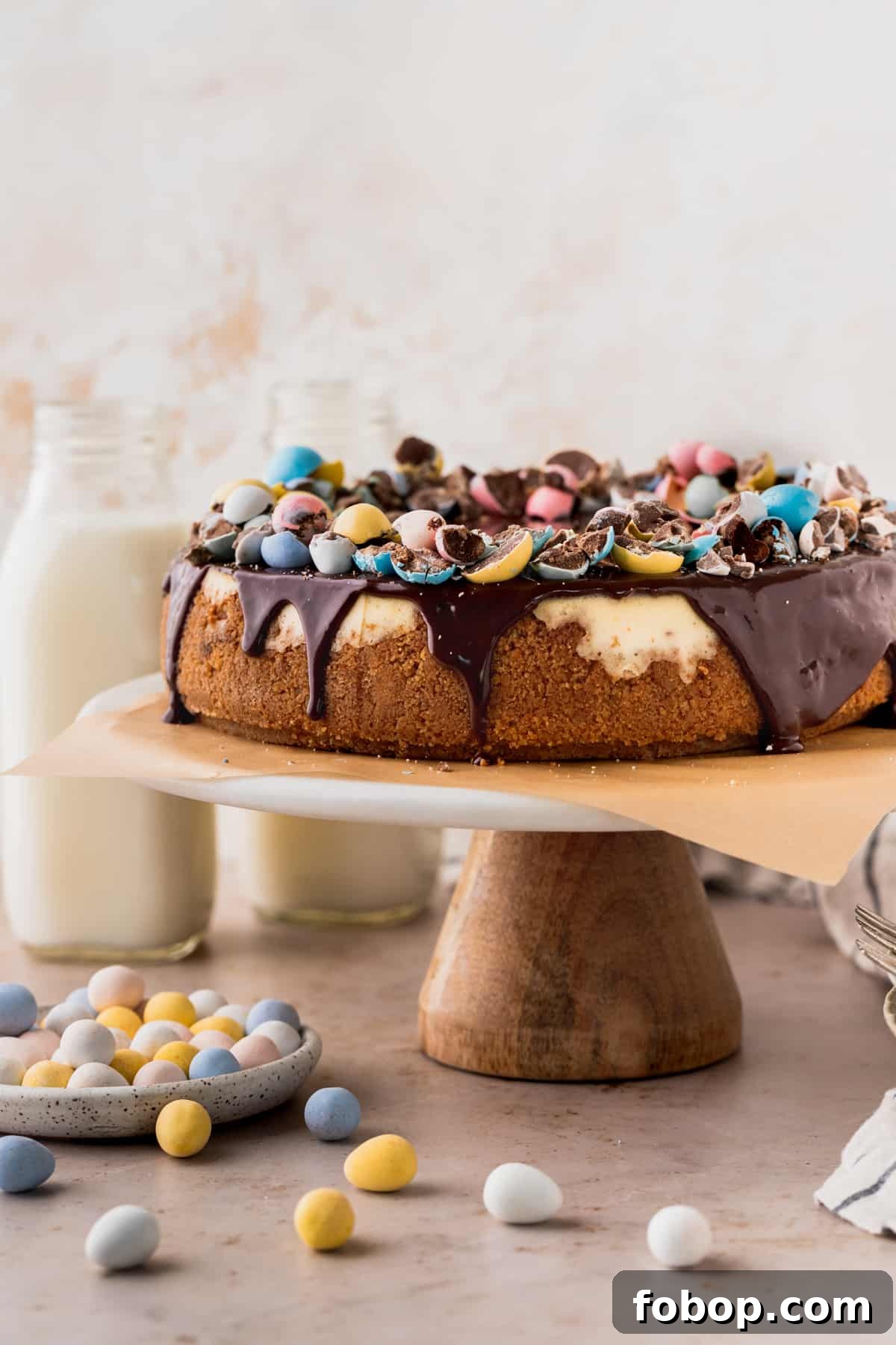 Easter Egg Cheesecake Recipe with Decorative Candy Topping 2 Easter egg cheesecake on a cake stand surrounding by mini eggs.