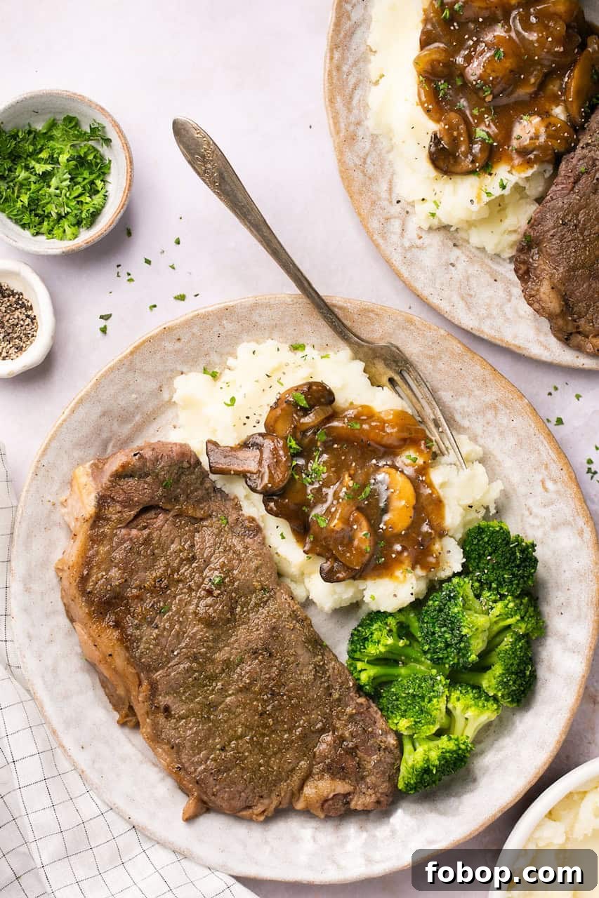 Instant Pot Steak in Rich Homemade Beef Gravy 6 Juicy New York strip steak topped with homemade beef gravy on a plate with mashed potatoes and broccoli.
