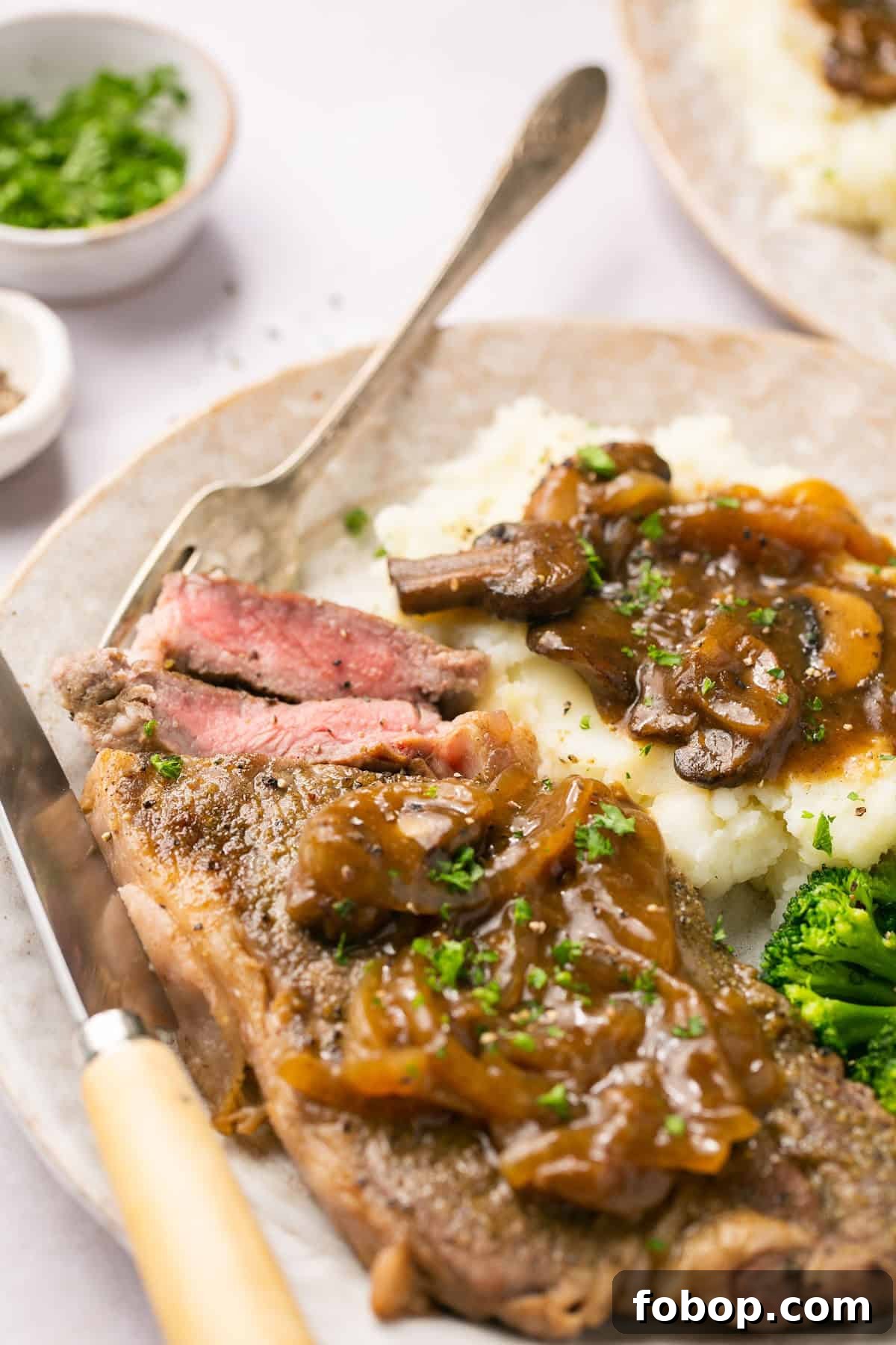 Instant Pot Steak in Rich Homemade Beef Gravy 7 Close-up of cut Instant Pot steak with rich onion-mushroom gravy, served with mashed potatoes and broccoli.