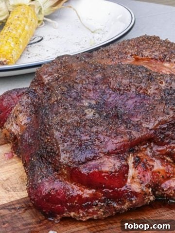 smoked pork butt on cutting board with corn in background