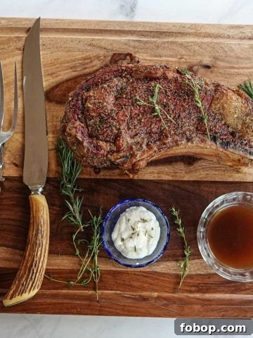 rib roast on cutting board with knife, fork, au jus, and horseradish sauce