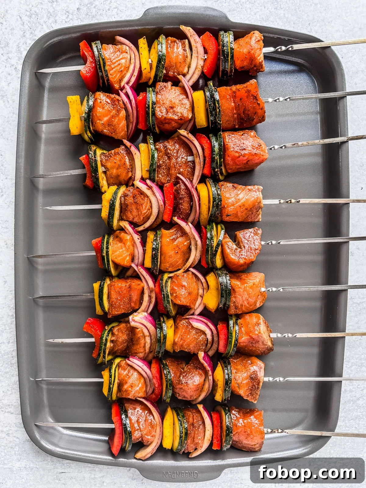 Uncooked salmon kebabs on a baking sheet.