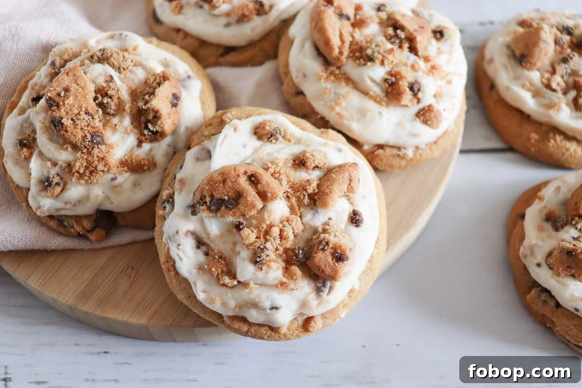 25 Office Cookies Everyone Brings and Raves About 11 Frosted chocolate chip cookie cookies on a wooden cutting board.
