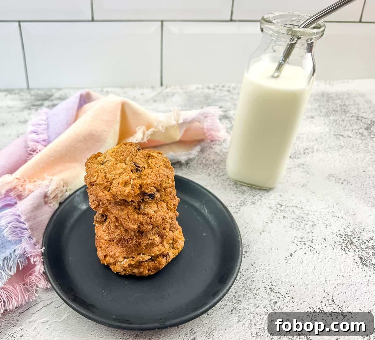 25 Office Cookies Everyone Brings and Raves About 22 Oatmeal raisin cookies on a plate next to a glass of milk.