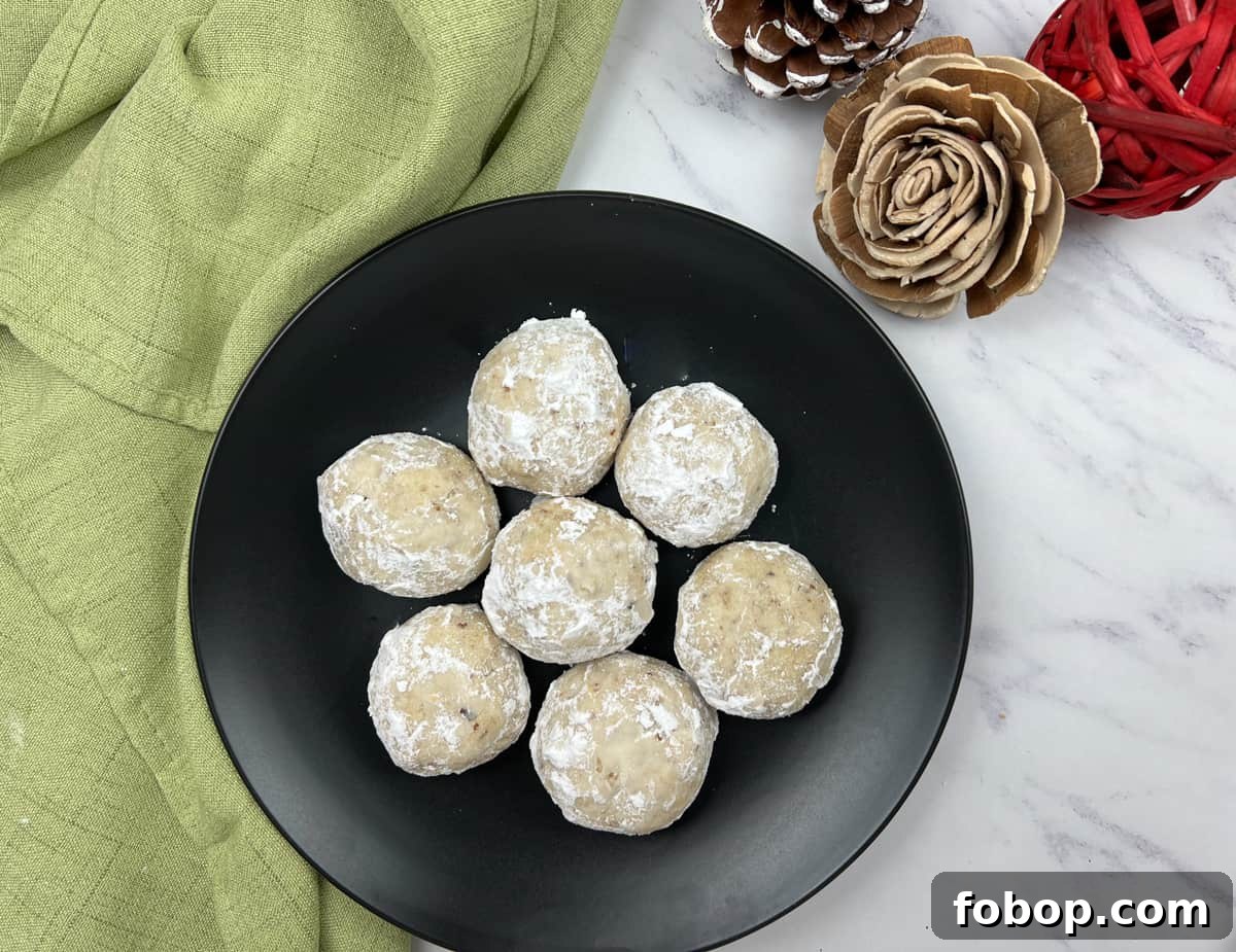 25 Office Cookies Everyone Brings and Raves About 26 Top-down shot of seven pecan butter balls on a black plate.