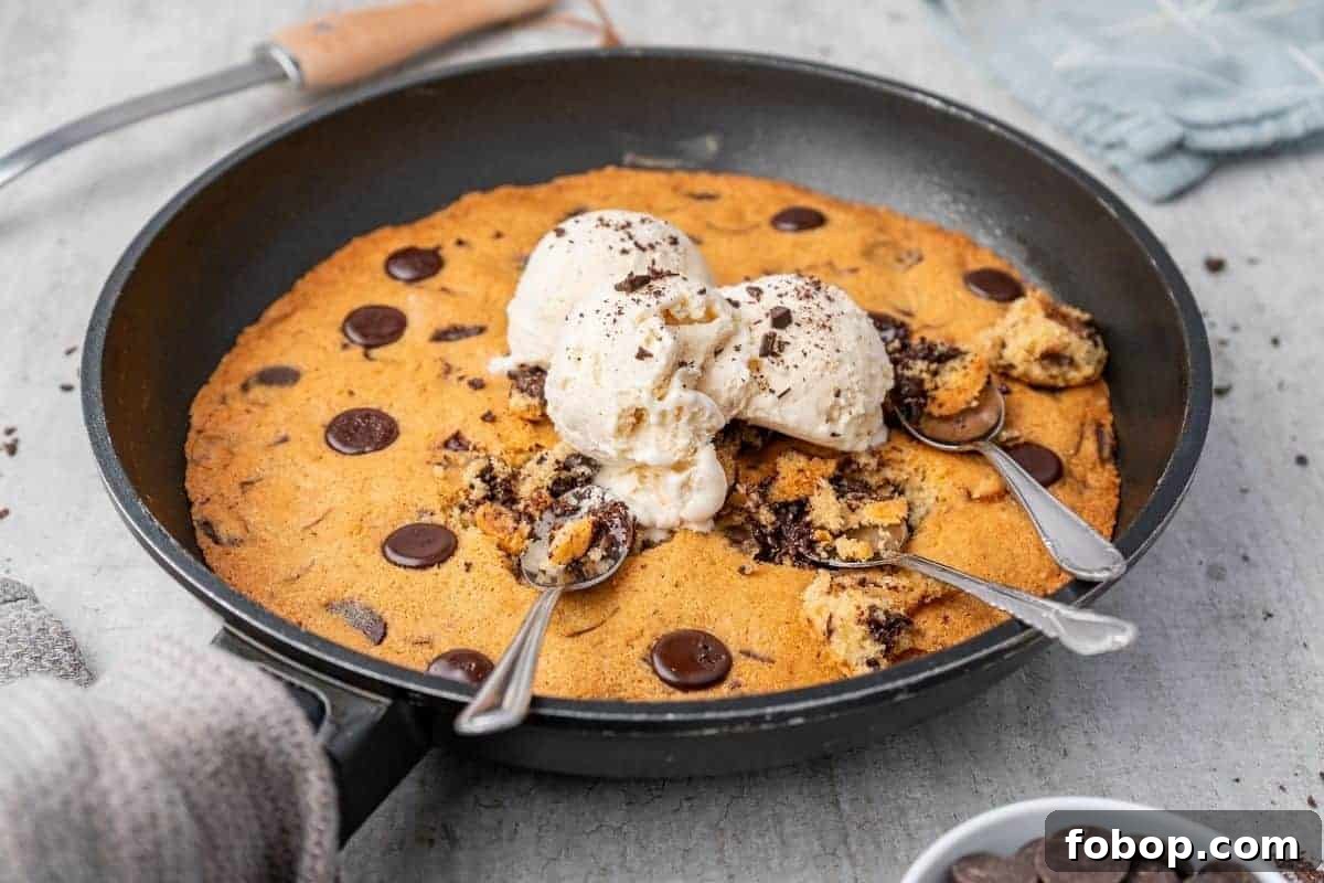 25 Office Cookies Everyone Brings and Raves About 27 Overhead shot of a warm chocolate chip skillet cookie in a black skillet, topped with scoops of vanilla ice cream and three spoons.