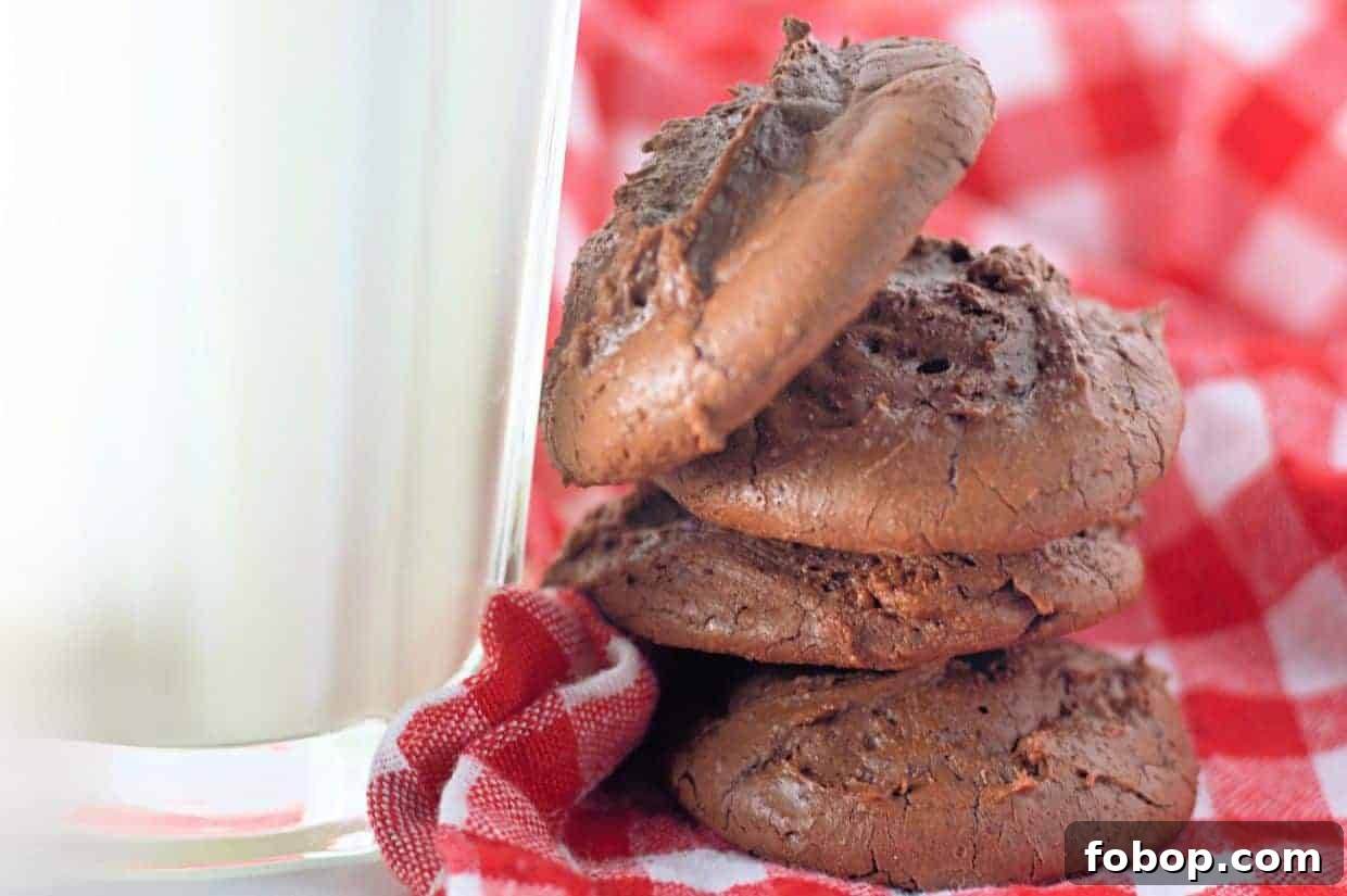 25 Office Cookies Everyone Brings and Raves About 7 Three Fudgy Chocolate Brownie Cookies stacked beside a glass of milk on a red and white checkered cloth.