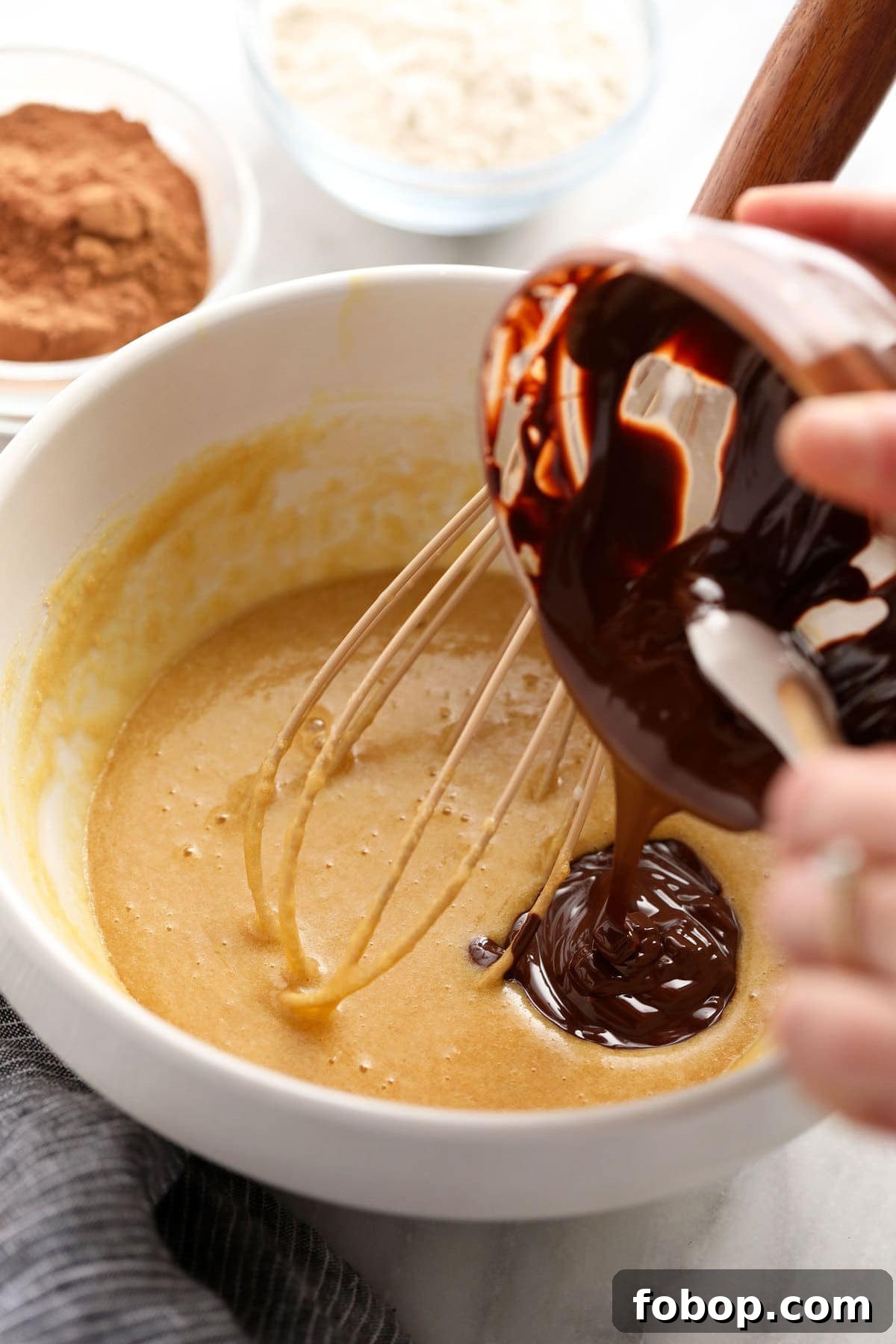 Ooey-gooey homemade fudgy brownies made with simple ingredients. You'll never want to eat another fudgy brownie recipe again! pouring chocolate into batter