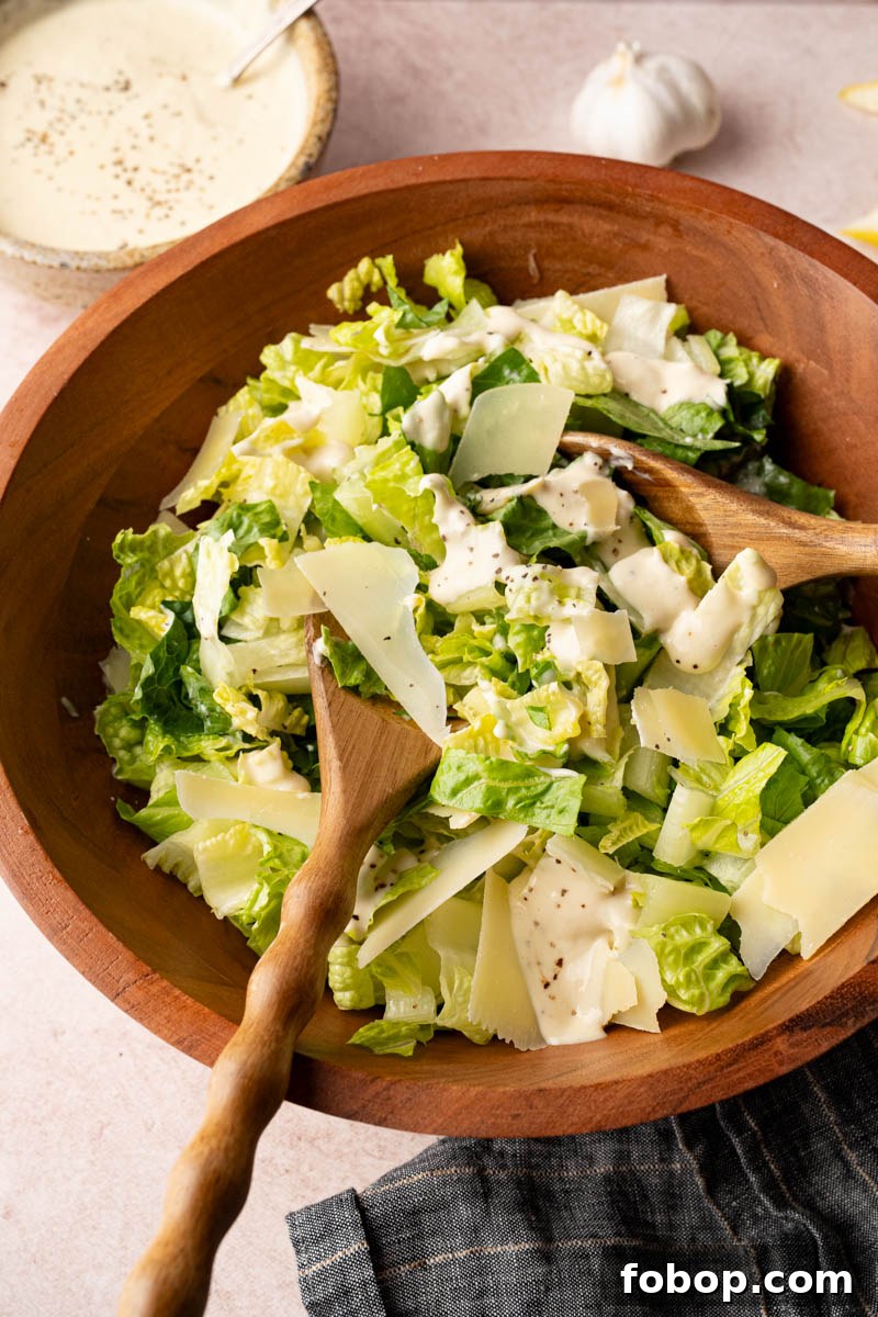 Tossing together the romaine lettuce, parmesan cheese and homemade caesar dressing in a wooden bowl before serving. 