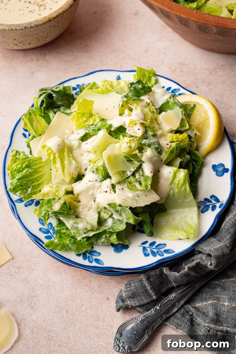 Caesar salad on a plate with a lemon wedge for serving.