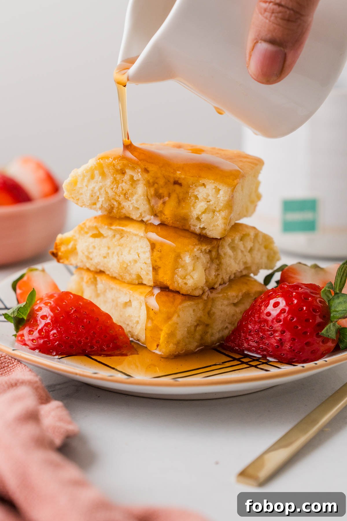 air fryer pancakes with syrup and strawberries on a plate.