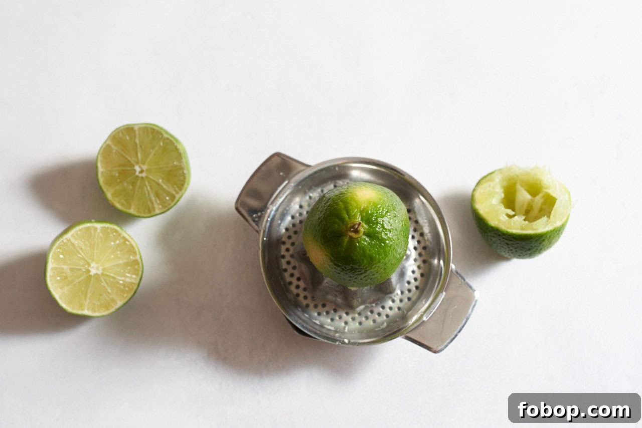 Smoky Mezcal Margarita Recipe: How to Make the Classic Cocktail 4 Half a lime on a juicer surrounded by limes that have been cut in half.