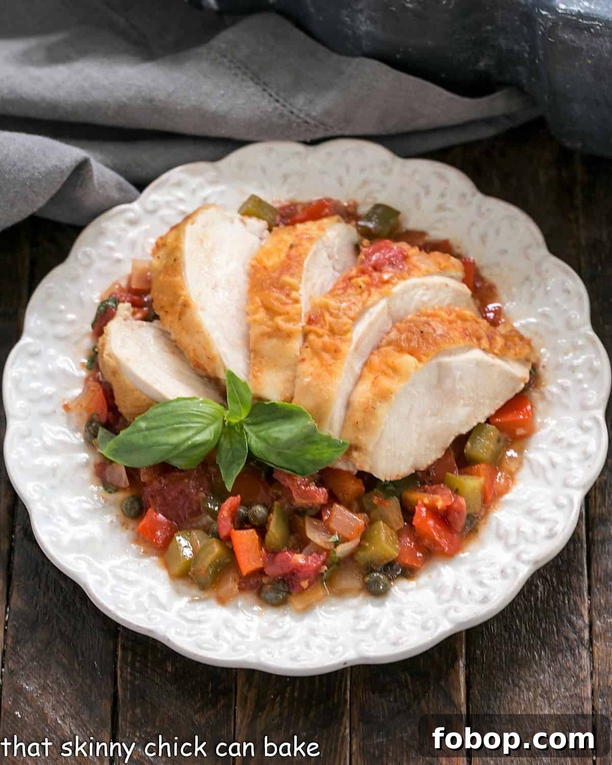 Easy Chicken Cacciatore - a classic Italian dish with tomatoes, peppers and herbs for an easy comforting dinner! Overhead view of Chicken Cacciatore fanned on a decorative white plate.