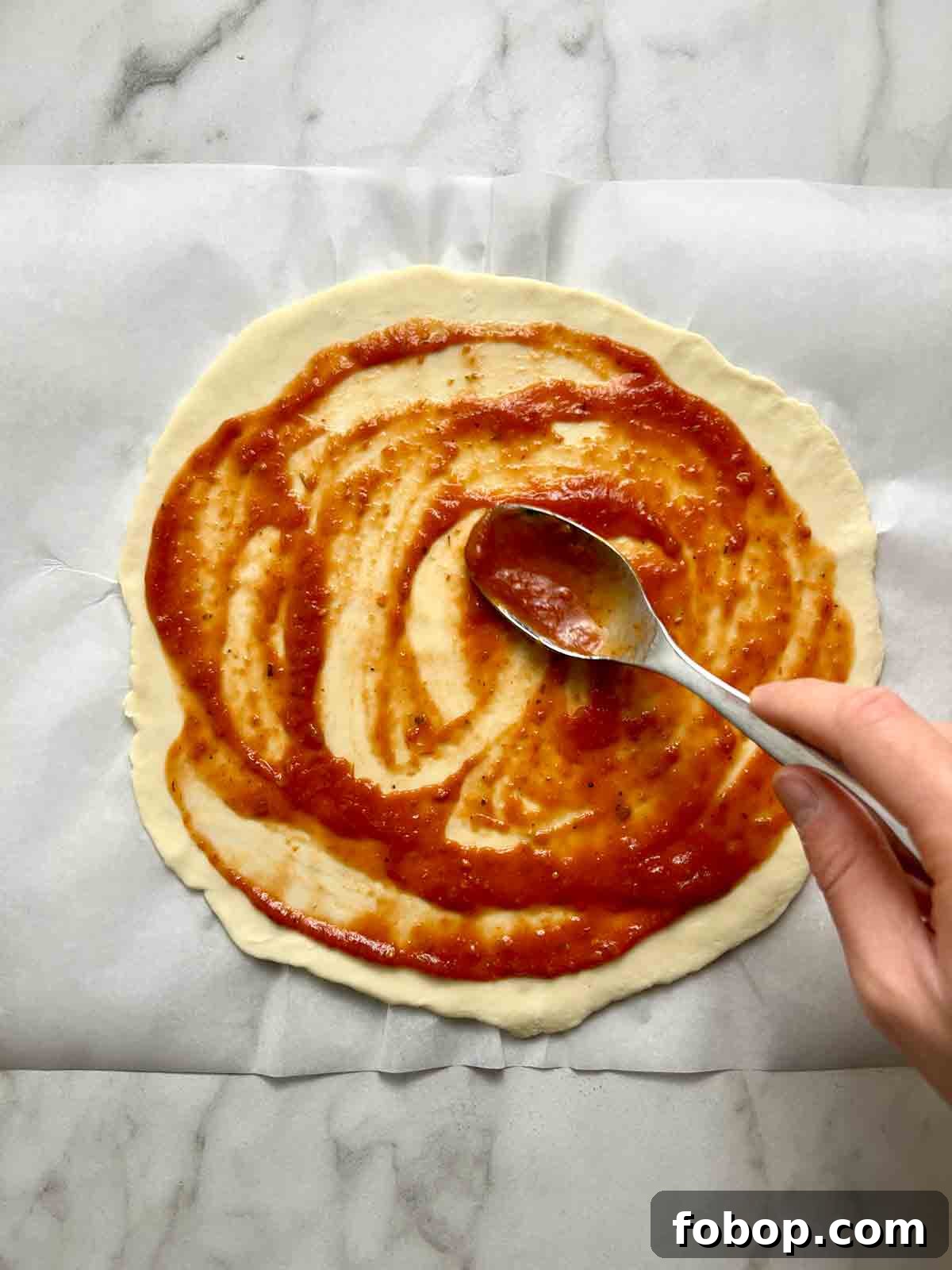 Crispy Cracker-Crust Pizza Recipe: Thin, Crunchy Homemade Pie 8 pizza sauce being spread on crust
