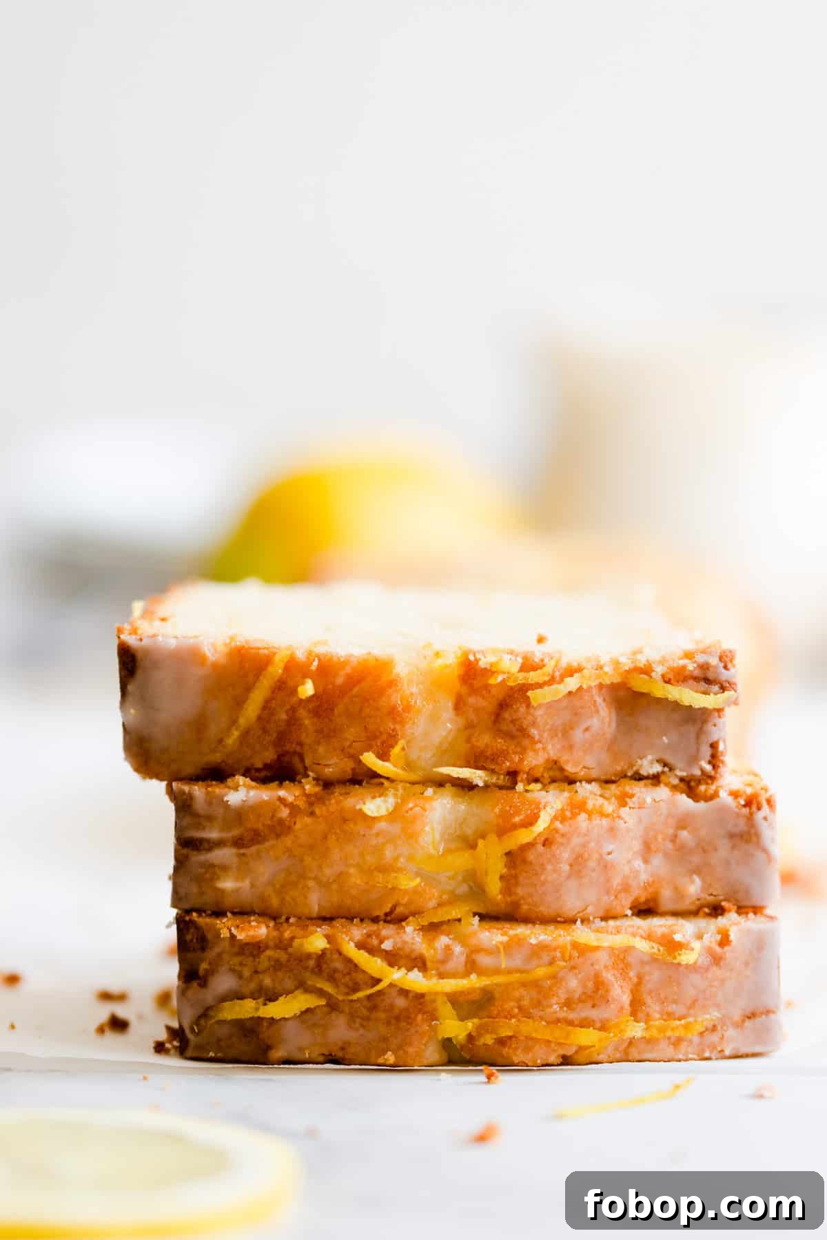 side close up of three slices of lemon drizzle cake stacked on top of eachother