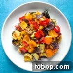 Spicy roasted vegetables on a white plate on a blue background.
