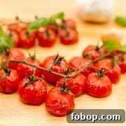 Roasted cherry tomatoes on the vine with basil and garlic on a butcher block cutting board