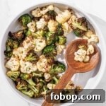 Air fryer broccoli and cauliflower with a wooden spoon.
