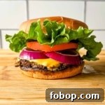A turkey smash burger on a wooden cutting board in front of subway tile.