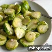 Marinated brussels sprouts are shown on a white plate with a spoon and a dark red linen.