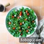 Arugula caprese salad on a white plate next to two forks.