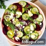 Beet cucumber salad with feta and dill in a pink dish.