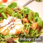 A bowl of burrata caprese salad with olive oil being poured over it.