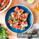 Watermelon salad garnished with mint and feta on a blue plate.