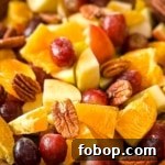 A closeup of Thanksgiving Fruit Salad with grapes, pears, apples, oranges, and pecans.