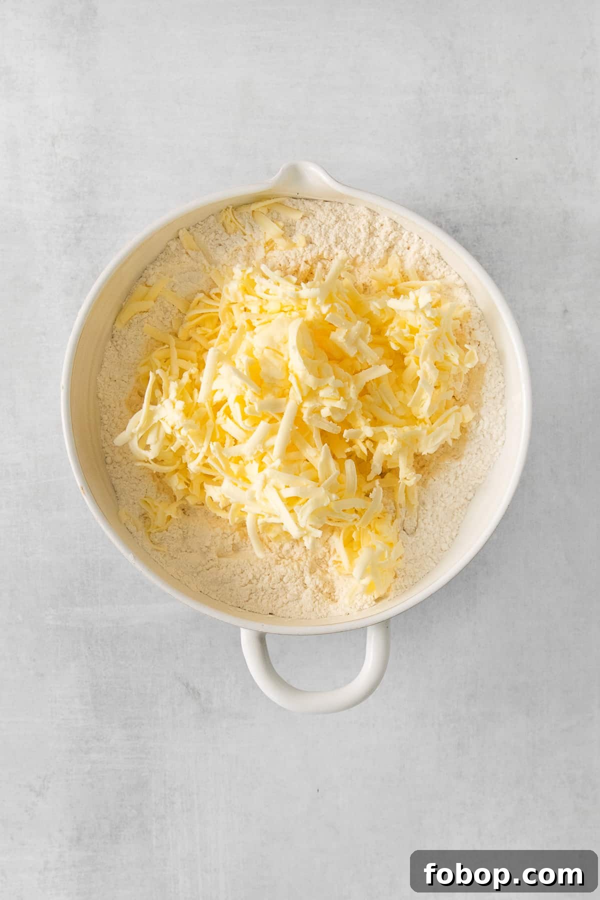 How to Make a Copycat Bacon Egg and Cheese Sandwich Recipe 6 shredded cheese in a white bowl on a grey background.