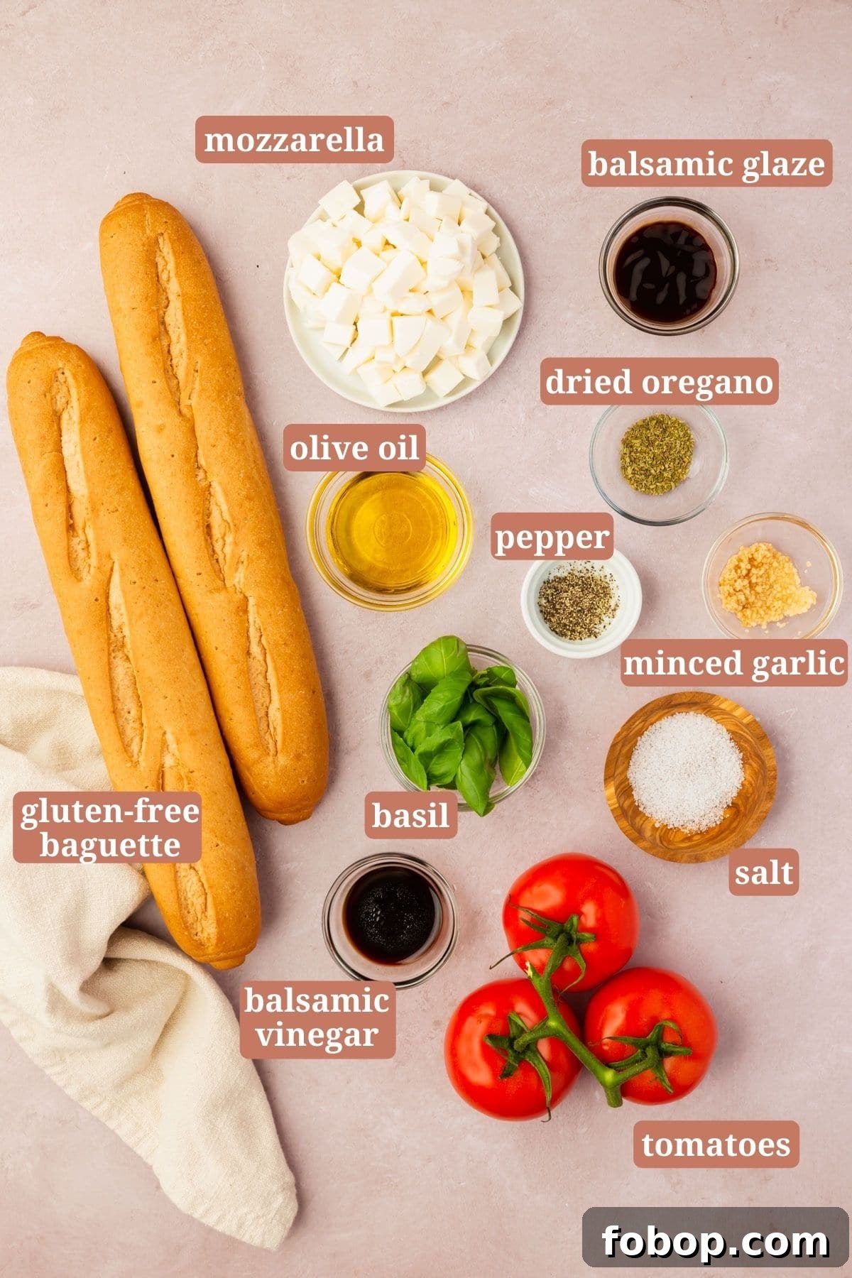 Ingredients for making bruschetta with mozzarella on a pink table: gluten-free baguette, mozzarella, balsamic glaze, basil, olive oil, pepper, oregano, garlic, salt, tomatoes and balsamic vinegar.