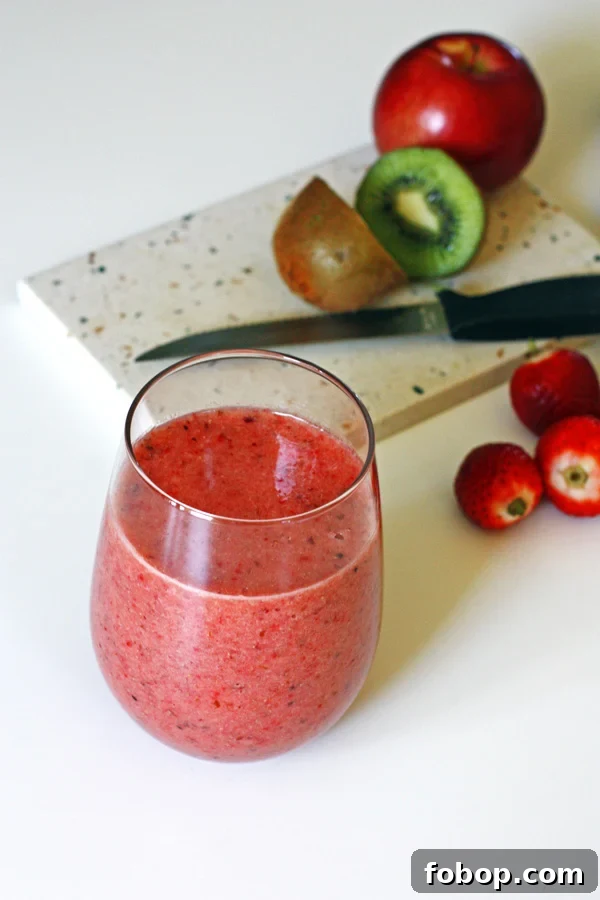 Smoothie with sliced fruit on cutting board with a knife