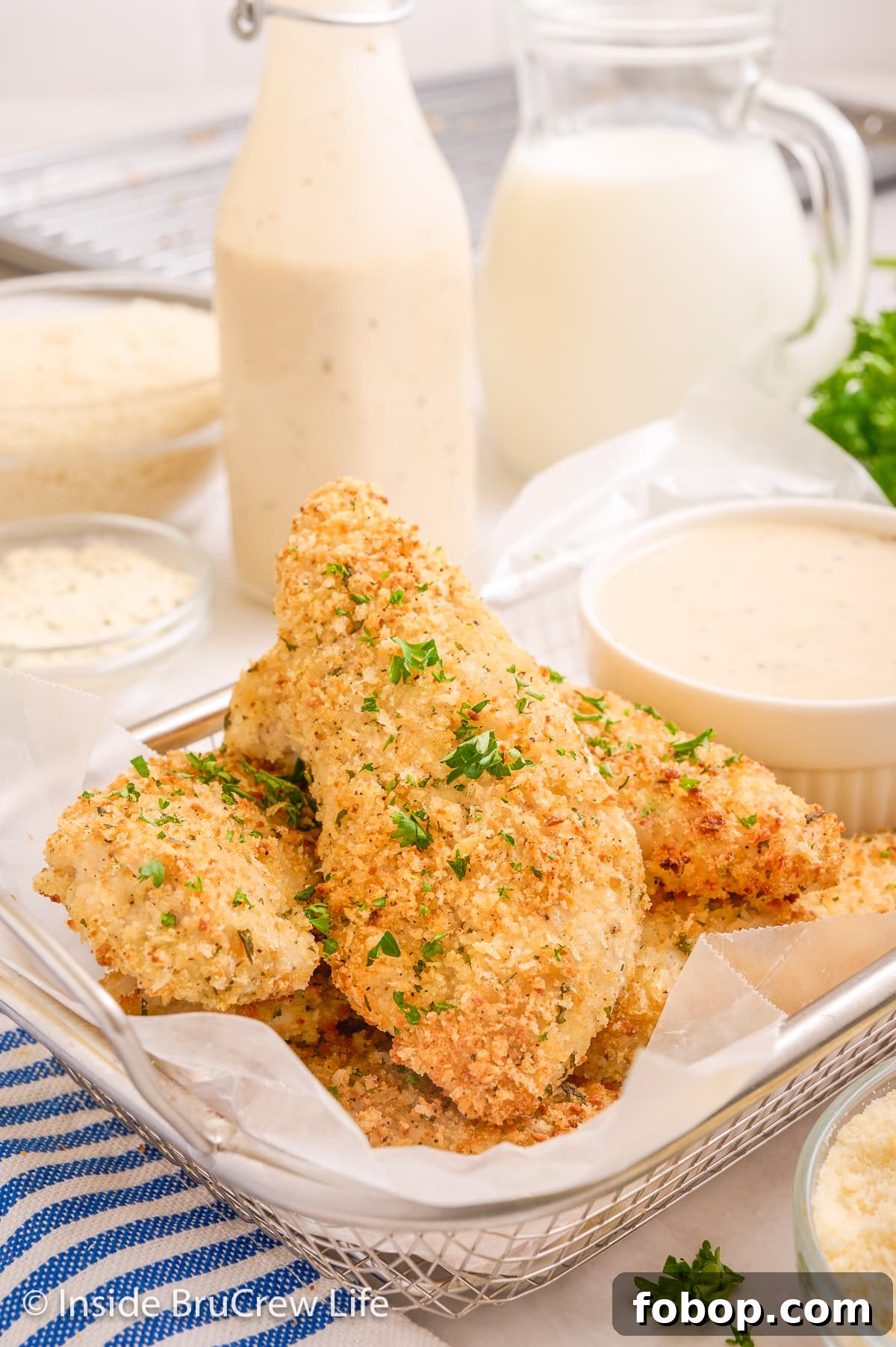 Crispy Parmesan Chicken Tenders with Garlic Herb Dipping Sauce 6 Baked chicken tenders in a wire basket with a cup of ranch.