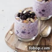 Creamy Blueberry Overnight Oats Recipe for Quick Breakfast 4 Blueberry overnight oats in a glass topped with frozen blueberries and sliced almonds.
