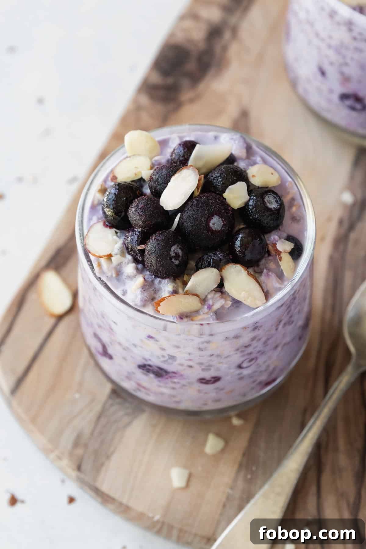 Creamy Blueberry Overnight Oats Recipe for Quick Breakfast 6 Frozen blueberries and sliced almonds on a glass of overnight oats.