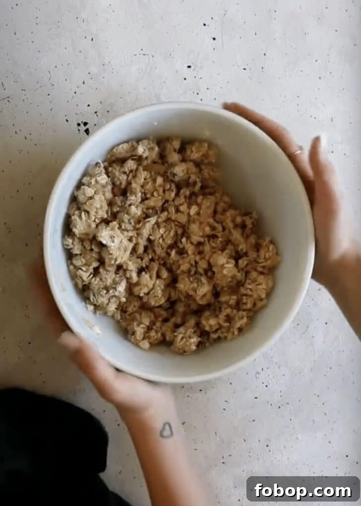 Maple Oat Streusel Pumpkin Crisp Recipe 6 Hands holding a white bowl of crumble.
