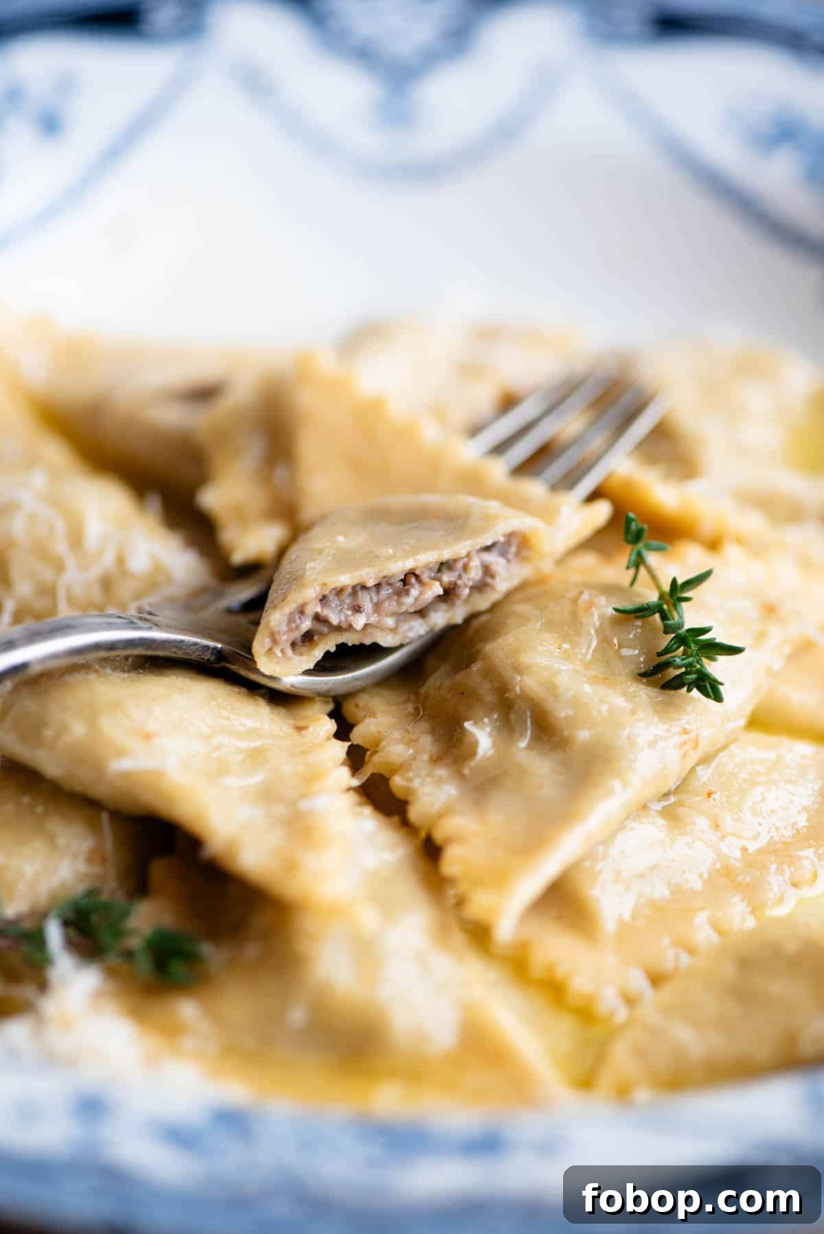 A close up side shot of mushroom and taleggio Triangoli pasta with one cut open to see the filling inside.