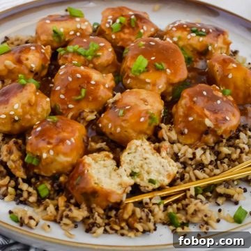 Sticky Asian Chicken Meatballs with Ginger Soy Glaze 9 Asian chicken meatballs over bed of rice on white plate with chopsticks.
