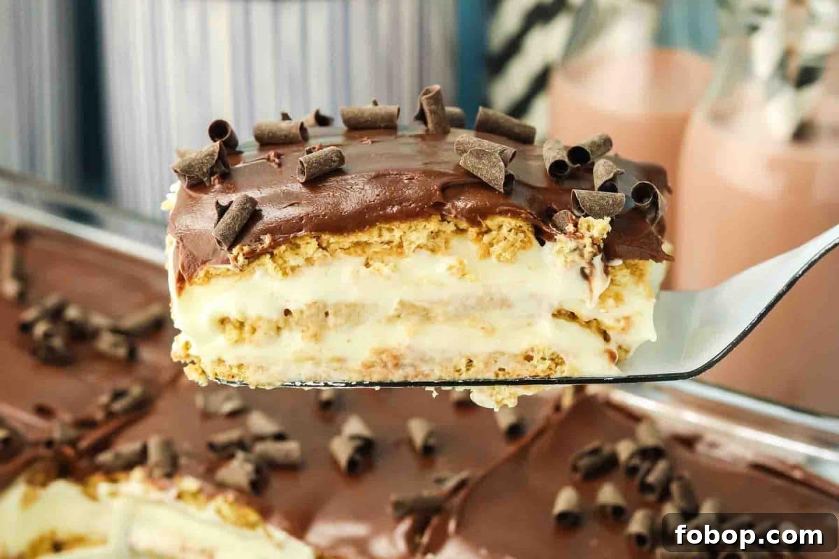No-Bake Chocolate Eclair Cake Recipe (No Oven Needed) 2 Slice of chocolate eclair cake on a spatula showing layers of graham crackers, vanilla pudding, and chocolate frosting - Hostess At Heart