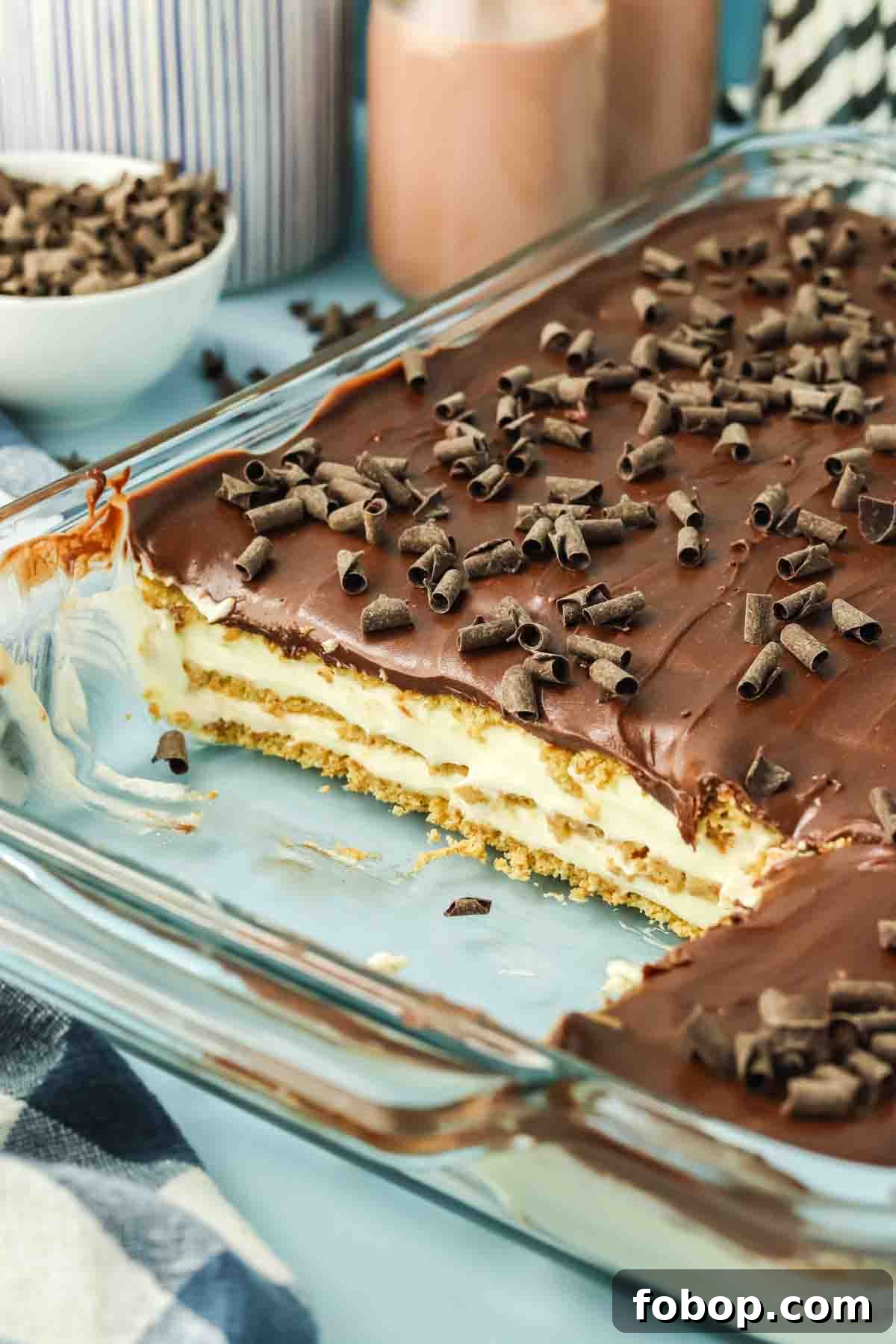No-Bake Chocolate Eclair Cake Recipe (No Oven Needed) 11 Close-up of a pan of no-bake eclair cake sliced and showing creamy pudding layers between softened graham crackers. Hostess At Heart
