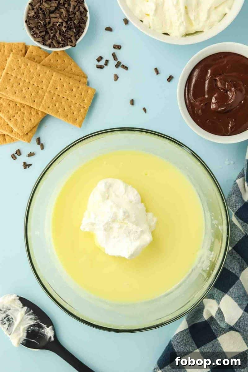 No-Bake Chocolate Eclair Cake Recipe (No Oven Needed) 5 Folding whipped topping into vanilla pudding mixture for chocolate eclair cake - Hostess At Heart