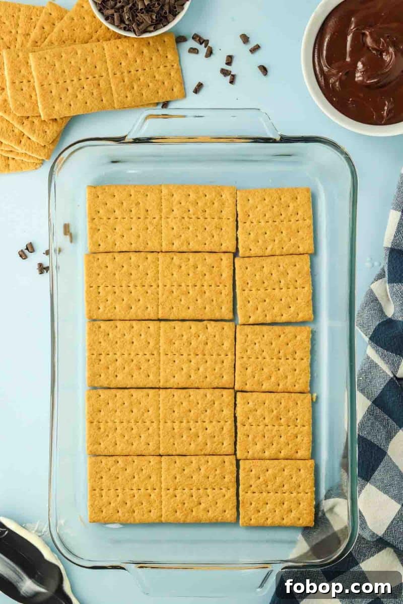 No-Bake Chocolate Eclair Cake Recipe (No Oven Needed) 6 A layer of graham crackers lining the bottom of a 9x13 baking dish - Hostess At Heart