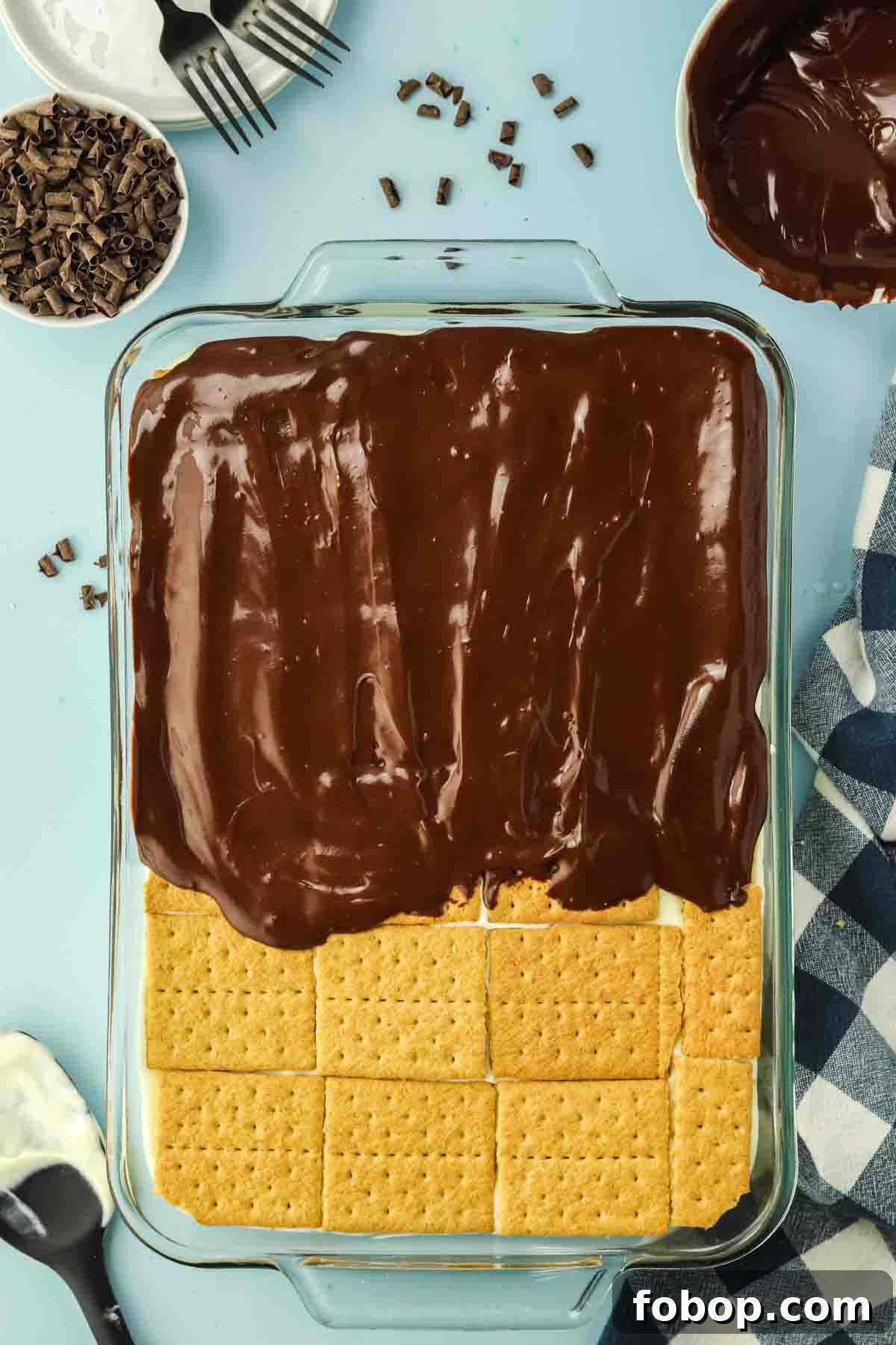 No-Bake Chocolate Eclair Cake Recipe (No Oven Needed) 9 Pouring warm chocolate frosting over top layer of graham crackers - Hostess At Heart