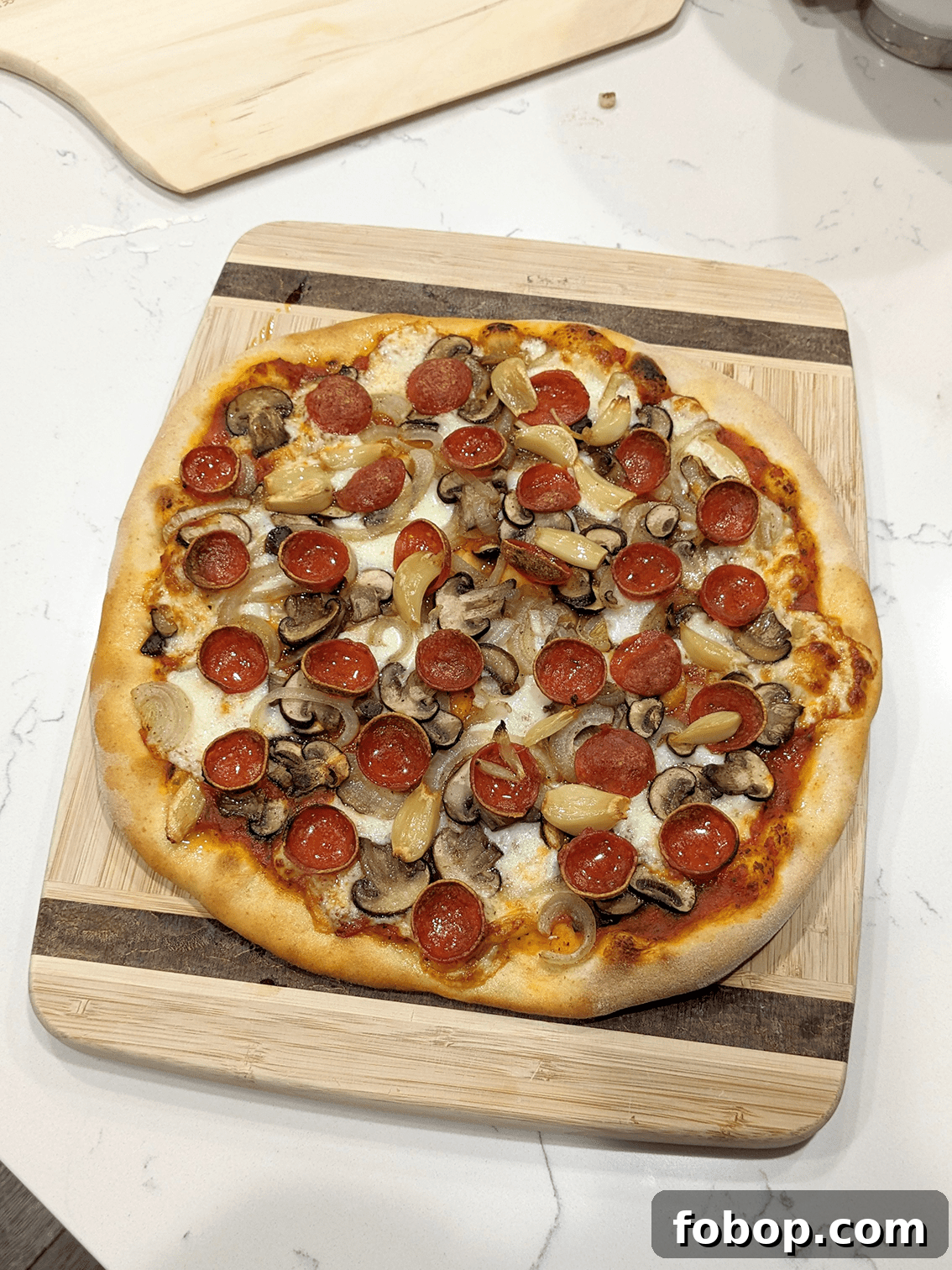 A homemade thin crust pizza on a wooden cutting board.