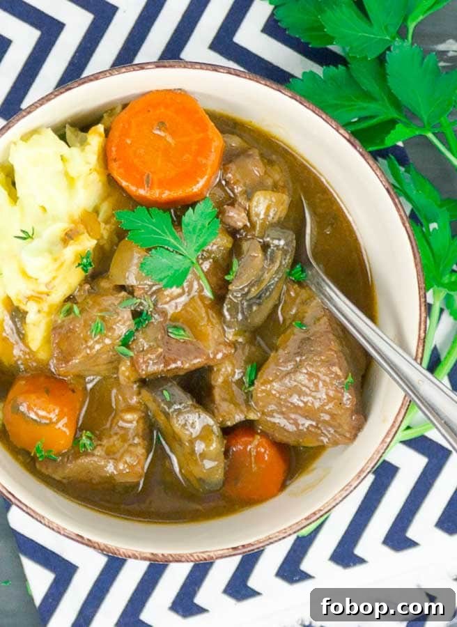 Beef and Guinness Stew in white bowl with mashed potatoes