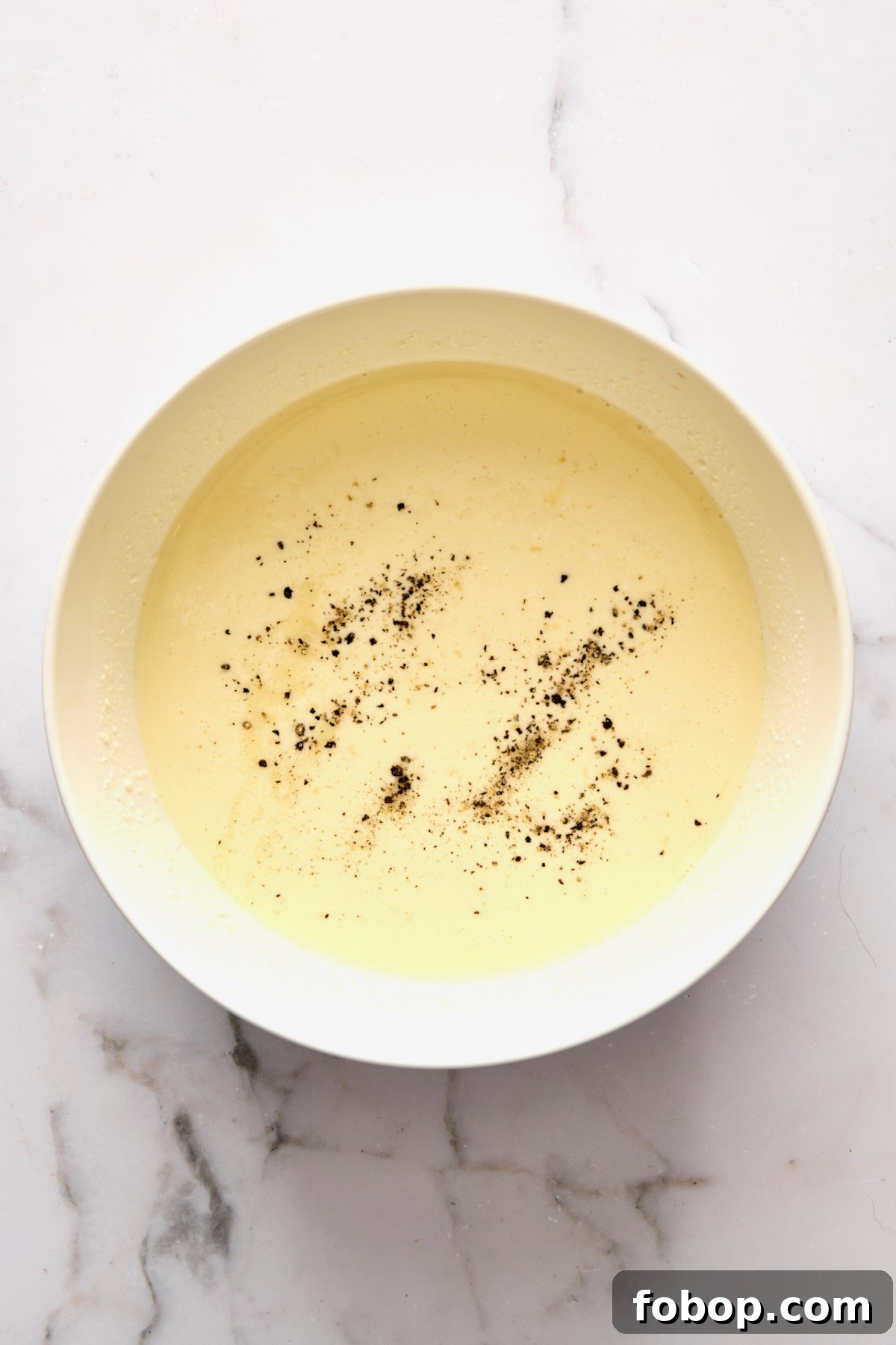 Custard for quiche in white mixing bowl.