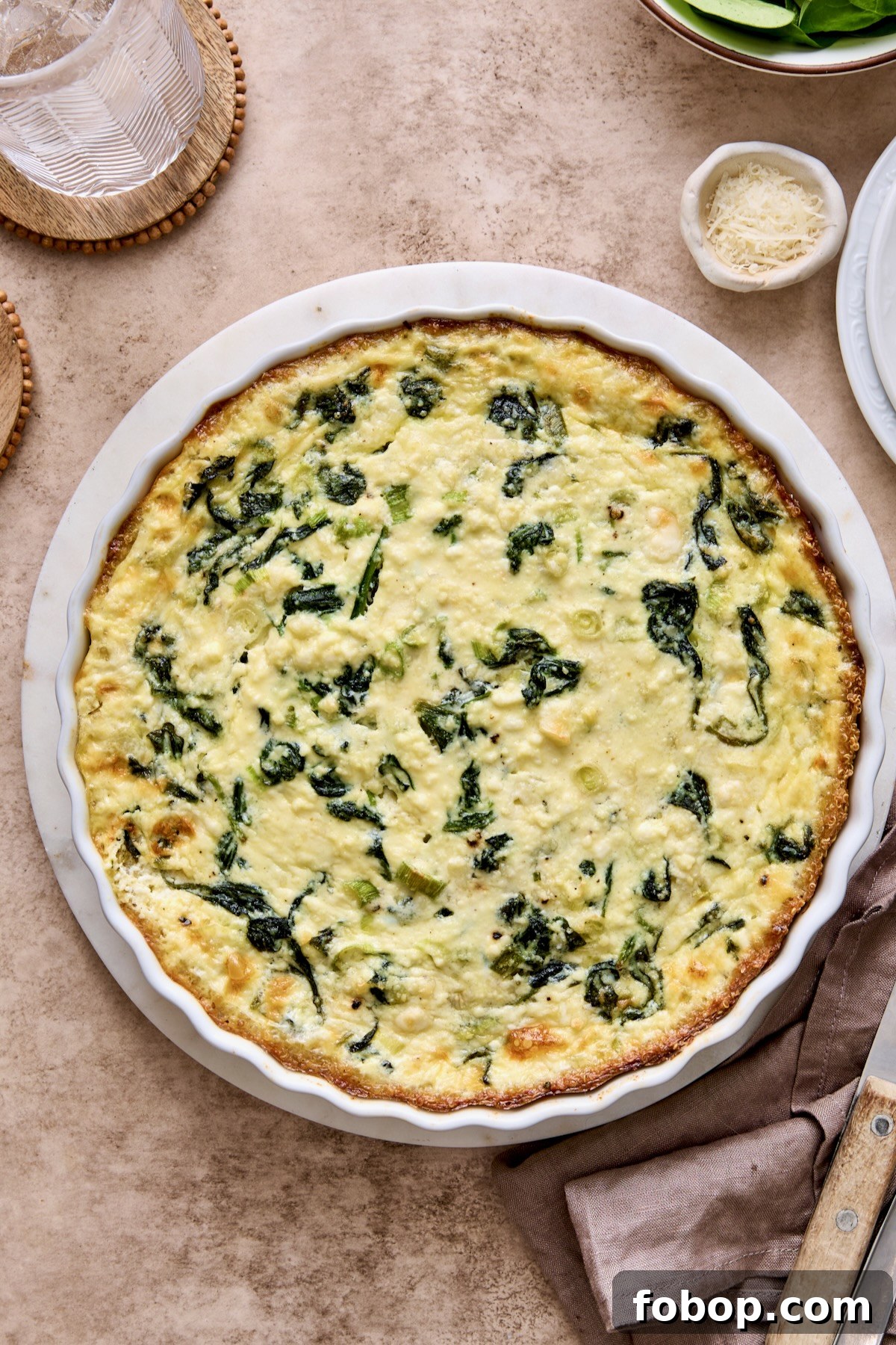Baked Spinach Feta Quiche with Quinoa Crust in round white baking dish.